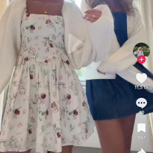 Blommig kortklänning med axelband - Superfin kortklänning med breda axelband och blommigt mönster i rosa, vinrött och grönt på en ljus bakgrund. Klänningen har en utställd kjol och markerad midja, perfekt för sommarens alla tillfällen. Materialet känns mjukt och luftigt. Helt ny men dragkedjan där bak är trasig 