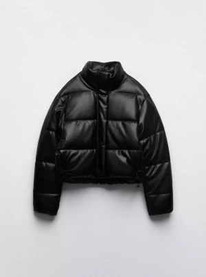 Svart croppad pufferjacka i skinnimitation - Snygg svart pufferjacka med croppad passform och hög krage. Jackan är quiltad och har en glansig yta i skinnimitation, perfekt för att lyfta din vinterstil. Långärmad och med dragkedja framtill.