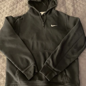 Svart Nike hoodie med huva, M🌻 - Svart hoodie från Nike i storlek M med klassisk logga på bröstet🖤 Tröjan har huva med snörning, magficka och långa ärmar. Perfekt för chill eller träning👟Anvent den fåtal gånger💞