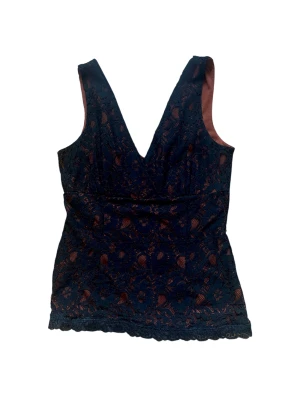 Svart spetslinne  - Svart spetslinne i storlek M. Toppen har blommigt spetsmönster med brun/rostfärgaf underton, djup v-ringning och är ärmlös.