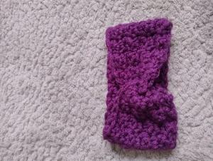 Lila virkat pannband med twist - Säljer ett chunky virkat pannband i lila med snygg twist framtill som jag gjortt själv. Perfekt för att hålla öronen varma och ge en cool touch till din look. Mjukt och tjockt garn som sitter skönt runt huvudet. Passar dig som gillar färg och vill sticka ut lite extra.