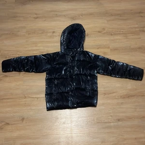 En svart/marinblåå dunjacka från Minoti!  - Säljer min supersnygga  svarta  pufferjacka från Minoti med glansig finish och huva!  Jackan har ett snyggt broderat märke  på ärmen och praktisk dragkedja. Nästan helt ny utan några defekter! PRIS KAN DISKUTERAS!💕