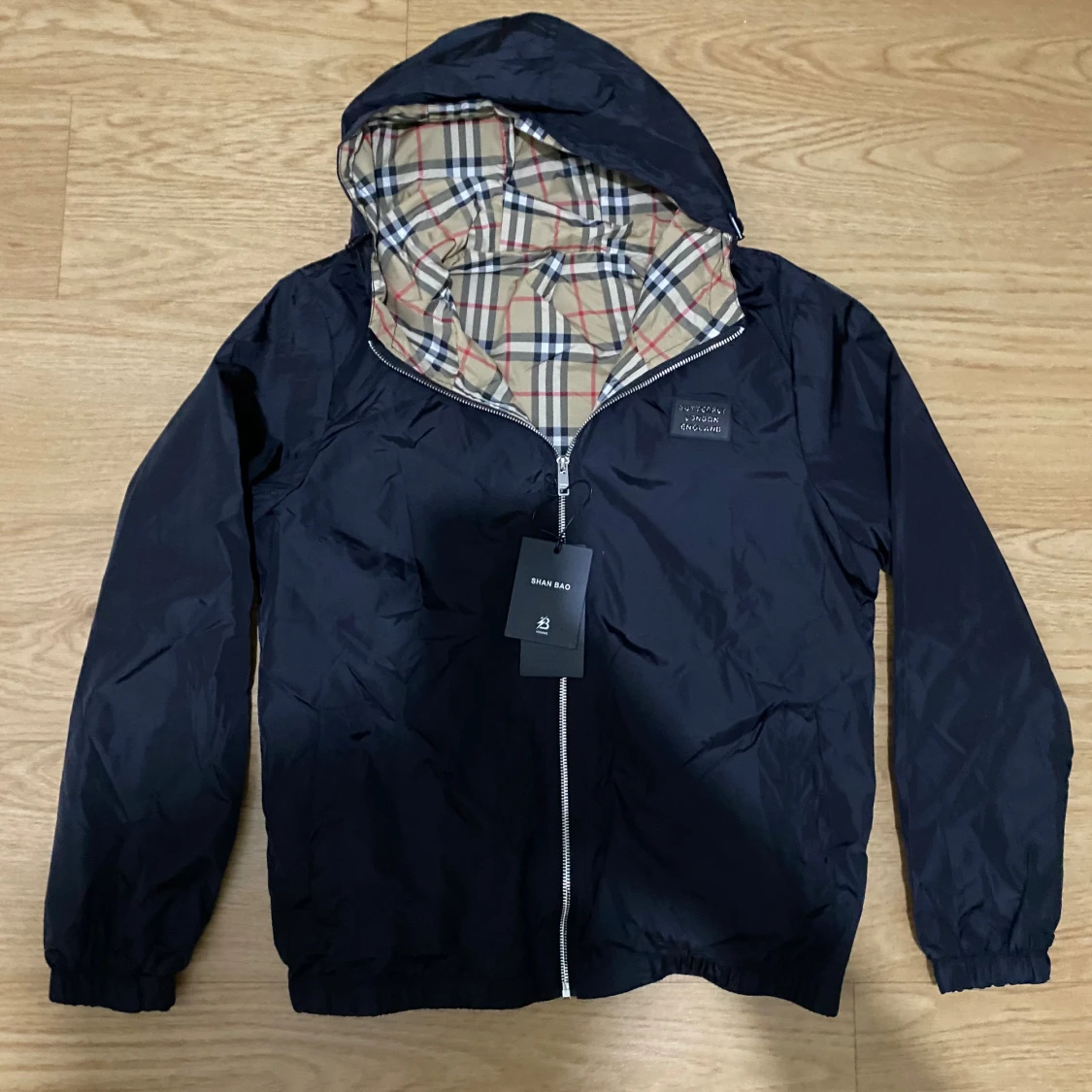 Svart vindjacka med rutig huva