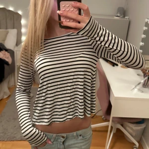 Randig croppad långärmad tröja - Säljer en svartvit randig långärmad tröja med croppad passform och rund hals. Tröjan är tillverkad i mjuk bomull och har en loose fit som ger en chill vibe. Perfekt att matcha med jeans eller shorts för en avslappnad look.