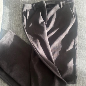 Kostymbyxor  - Snygga svarta kostymbyxor med hög midja och rak passform. Perfekta för en stilren look. Byxorna har diskreta fickor och en klassisk design. Storlek xxs med längd 32