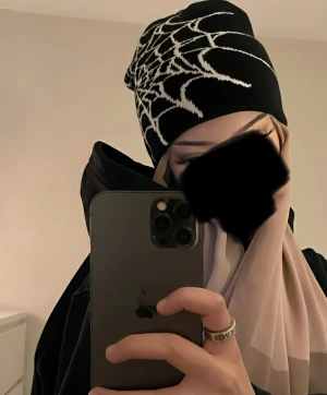 Svart mössa med spindelnätsmönster - Cool svart mössa med vitt spindelnätsmönster, perfekt för dig som gillar edgy stil. Mössan är stickad och har en mjuk, skön passform som sitter snyggt på huvudet. Passar till både streetwear och chill outfits.