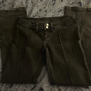 Svarta lågmidjade jeans - Svarta/mörkgråa jeans med streck och två knappar vid midjan. Lite slitna benslut med inget som syns väl med skor. Strl 29 vilket jag skulle säga motsvarar M. Kontakta gärna mig om frågor!💞