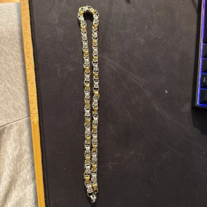 Kraftigt kedjehalsband i guld och silver - Säljer ett chunky halsband med boxkedja i både guld- och silverfärgade länkar. Kedjan har en cool, industriell look och stängs med en karbinhake. Perfekt för dig som gillar att sticka ut med accessoarer som har lite edge.