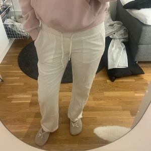 Vita linnebyxor med snörning - Säljer ett par vita linnebyxor med skön passform och snörning i midjan. Byxorna har raka ben, praktiska fickor framtill och är perfekta för chill dagar. Materialet är luftigt linne och färgen är fräsch vit. Passar dig som gillar avslappnad stil.