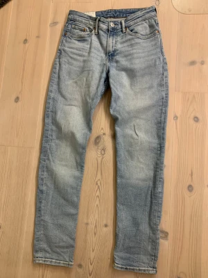 Slim fit ljusblå jeans från H&M - Slim fit jeans från H&M i ljusblå tvätt med klassisk femficksdesign och raka ben. Jeansen har normal midja och är tillverkade i mjukt bomullsmaterial med lite stretch för skön passform. Perfekt för dig som gillar en clean och enkel stil.