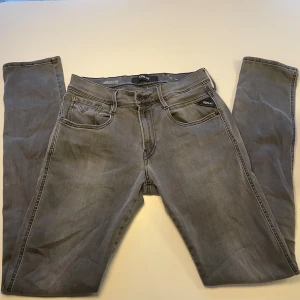 Replay Anbass grå - Snygga grå jeans från Replays ”Anbass” slim fit-modell. Klassisk femficksdesign med svarta detaljer och logotyp på bakfickan. Jeansen har normal midja och raka ben, tillverkade i mjukt jeansmaterial som sitter skönt runt benen.  Modellen på bilden är 173cm lång. Slå bara en pling 🛎️ ❗️kring några funderingar.
