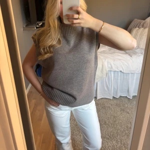 Stickad topp med polokrage  - Säljer en brun/grå stickad topp med ribbad hals och nederkant med polokrage. Modellen är ärmlös och har en rak, loose passform som ger en chill vibe. Perfekt att styla med jeans eller kjol för en enkel och snygg look. Den har blivit lite mindre i tvätten, så skulle väl säga att den passar en S mer än M. Superfint skick!