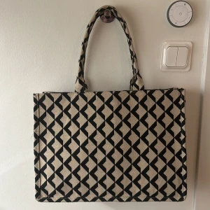 Beige och svart väska - Snygg väska från H&M i beige och svart med rutigt mönster. Perfekt storlek för att bära med sig allt man behöver under dagen.