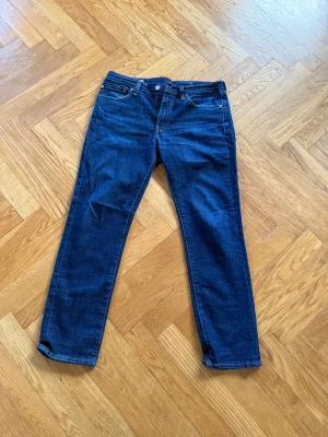 Levi's 511 blå jeans W32 L30 - Säljer ett par klassiska Levi's 511 jeans i mörkblå denim. Modellen är slim fit med raka ben och normal midja. Jeansen har fem fickor, dragkedjegylf och snygga kontrastsömmar. Perfekta för en stilren och avslappnad look.
