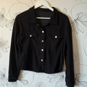Jacka / skjorta - Svart jacka/skjorta. Ribbad med två bröstfickor knappar frampå och i ärmarna. Köpt från temu för 102kr och aldrig använd. Storlek m