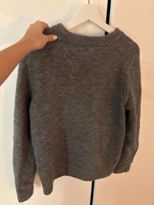 Grå stickad tröja från Zara - Mysig grå stickad tröja från Zara med rund hals och ribbade muddar vid ärmslut och nederkant. I strl 152 men passar mig med xs-m