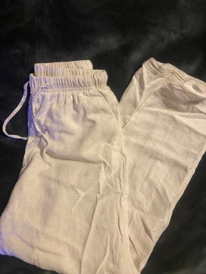Beige linnebyxor från Bershka XXS - Säljer ett par ljusbeige linnebyxor från Bershka i storlek XXS. Byxorna har elastisk midja med snörning och är tillverkade i ett luftigt linnematerial. Perfekta för chill dagar och har en relaxed passform med raka ben.
