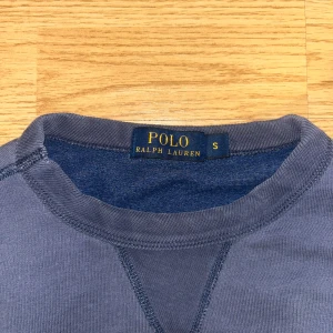 Blå sweatshirt från Polo Ralph Lauren - Sugen på något nytt? Tröjan ifrån polo Ralph lauren med ett gult snyggt tryck. Tröjan sitter fint runt kroppen i storlek S. Har en fantastisk dragning med sömmar syda i perfektion. Hör av du om du har någon fundering. MVH LUNDGRENS 