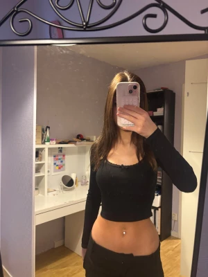 Svart croppad långärmad topp.  - Säljer en svart croppad topp med långa ärmar och ribbad struktur. Toppen har en söt liten rosett framtill och en rund urringning som ger en snygg look. 