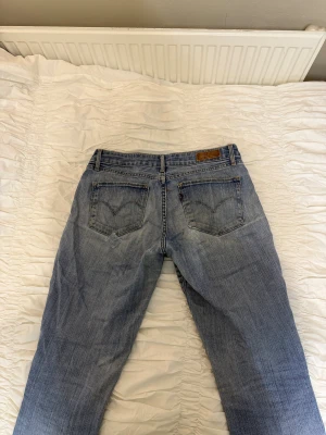 Levis  - Ljusblå Levis bootcut jeans och låg midja. Jeansen har slitningar och lagningar på benen och omsydd för en unik look, fem fickor och Levis-märke bak. Säljs bara för att de inte kommer till användning!! Storlek : är inte helt säker men skulle nog säga S eller liten M 💓