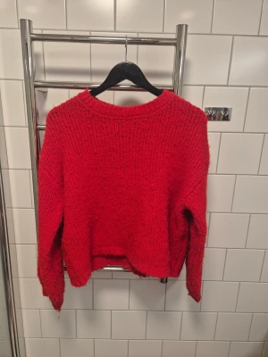 Röd stickad tröja från Pieces - Mysig röd stickad tröja från Pieces med grov struktur och rund hals. Tröjan har långärmade ärmar och en loose passform.