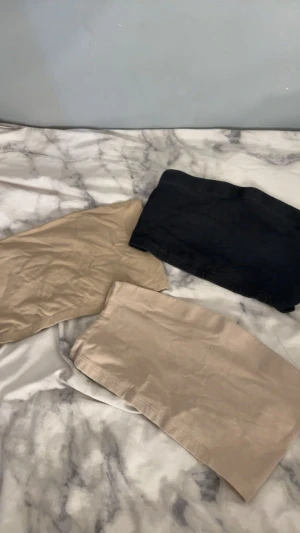 Tre basic toppar i svart och beige - Säljer tre par enkla toppar i olika färger: ett par svarta, ett par ljusbeige och ett par sandbeige. Alla är raka i modellen och har en clean look utan synliga detaljer. Perfekta för chill dagar och passar till det mesta. Materialet känns som mjuk bomull.