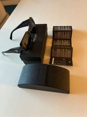 Prada symbole Solglasögon - Prada symbole solglasögon till ett billigt pris,  knappt använda och i nyskick, mörkgrå lins (mörkare högre i synfältet o ljusare lägre i synfältet) 100% UV skydd