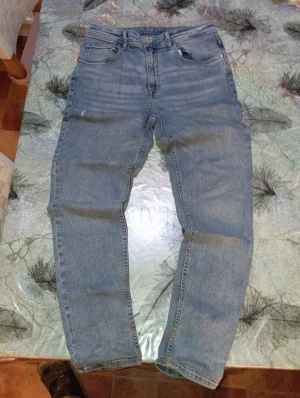 Blå tapered jeans från H&M - Säljer ett par blå jeans från H&M i relaxed tapered fit. Klassisk femficksmodell med normalhög midja och avsmalnande ben. Jeansen är tillverkade i denim och har snygga kontrastsömmar. Perfekta för en avslappnad och trendig look.