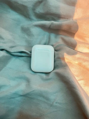 Apple AirPods (1st/2nd gen) med laddningsetui - Säljer ett par Apple AirPods med original laddningsetui. Hörlurarna och etuiet visar tecken på normalt slitage men är i fungerande skick. Perfekt för dig som vill ha trådlösa hörlurar till din iPhone eller annan enhet med Bluetooth.