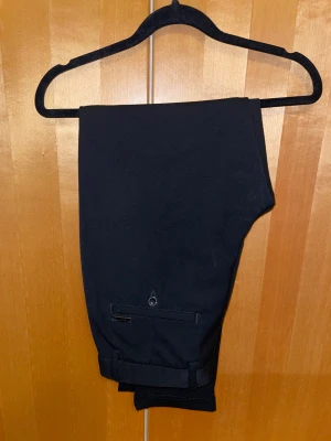 Svarta kostymbyxor - Ett par supersnygga kostymbyxor köpta från Jack&Jones. Köpta för ca 699kr för ett par år sedan men har använt de endast en gång. De är i storlek W31/L30 och lite slim. De är inte uppsydda men är sydda så de går att sprätta upp 5 cm där nere. De är super bekväma eftersom att tyget är lite stretchigt. Perfekta för ett lite mer uppklätt tillfälle. Skriv vid minska fråga! 