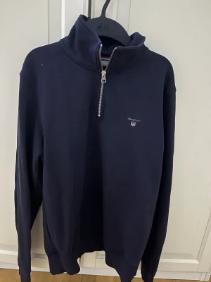 Gant Mörkblå half zip  - Snygg Gant half zip i färgen Marinblå. Den är i storlek M, men passar bra om du vanligtvis har S då den är lite liten i storleken. Den är i fint skick och kostar 1100kr ny.
