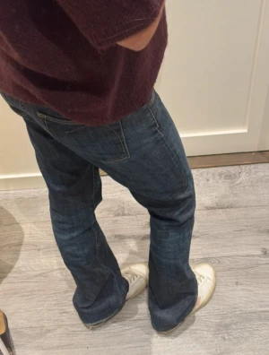 Blåa vintage jeans  - Snygga blå jeans med klassisk bootcut-passform. Jeansen har en rak siluett upptill och lätt utsvängda ben, vilket ger en chill vibe. Tillverkade i slitstarkt denim med fem fickor och diskreta sömmar. Perfekta för dig som gillar en avslappnad stil.