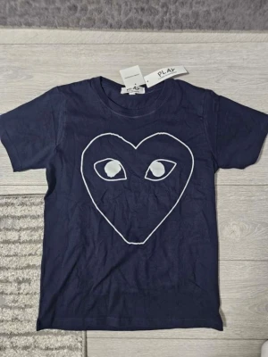 Mörkblå CDG Play t-shirt - Säljer en blå och rintigt skön cdg t shirt. Står S på tröjan men skulle säga att den lutar sig lite mer mot xs. Vid frågor är det bara att höra av sig✌️👌
