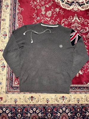 Grå stickad tröja med brittisk flagga från Henri Lloyd - Skitsnygg och unik stickad tröja från Henri Lloyd. Den har en brittisk flagga på axeln som ser jättecool ut. Väldigt bra skick. Storlek S. Hör av er vid funderingar 🙌