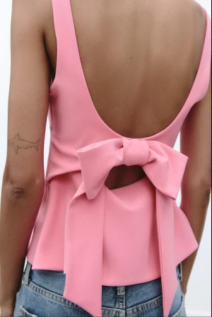 Rosa omlottopp med rosett i ryggen - Säljer en ljusrosa omlottopp med breda axelband och öppen rygg. Toppen har en stor rosett bak och är figursydd med lätt utsvängd nederkant. Skitsnygg!! 💕