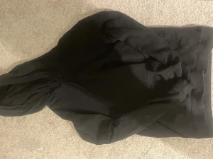 Svart hoodie i ekologisk bomull XS - En klassisk svart hoodie i ekologisk bomull, perfekt för dig som gillar en enkel och clean stil. Tröjan har huva med snörning och en stor magficka framtill. Passar dig som vill ha en basic och bekväm look.