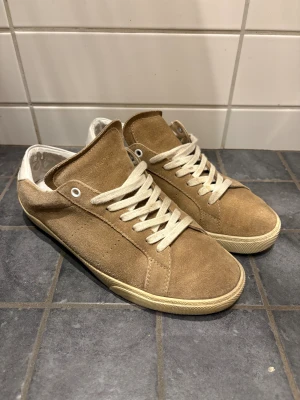 Saint Laurent skor - Snygga beigea sneakers från Saint Laurent. Storlek 40 men sitter en storlek större så passar om du har 41. Använda men i rätt bra skick. OG ingår, priset kan diskuteras!