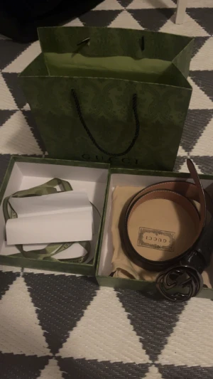 Svart skärp från Gucci med GG-spänne - Säljer ett svart bälte från Gucci i skinn med det ikoniska GG-spännet i metall. Bältet har klassisk design och kommer med originalförpackning, dustbag och kvitto. Perfekt accessoar för att lyfta vilken outfit som helst.