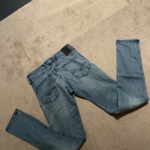 Replay ljusblå jeans straight fit - Säljer ett par ljusblå jeans från Replay med klassisk femficksdesign och snygga detaljer på bakfickorna. Jeansen har rak passform och är tillverkade i mjukt denimtyg. Perfekta för dig som gillar en avslappnad men stilren look. Storlek 31/34