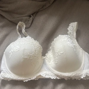 Intimissimi bh  - Superfin vit bh  med vadderade kupor och spetsdetaljer längs kanterna och axelbanden. Bhn är helt oanvänd.