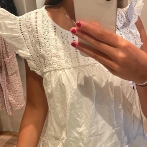 Vit blus med spets och volangärm - Supersöt vit blus med broderade spetsdetaljer och volangärmar. Luftig modell med romantisk känsla och fina hålbroderier upptill. Perfekt till jeans eller kjol för en fräsch look🩷🩷🩷🩷