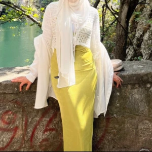 Ljusgul långklänning med slits - Säljer en elegant ljusgul långklänning med smal passform och slits framtill. Klänningen har en mjuk, glansig yta och är perfekt för dig som gillar stilrena och färgstarka plagg. Passar dig som vill sticka ut med en fräsch och somrig look.