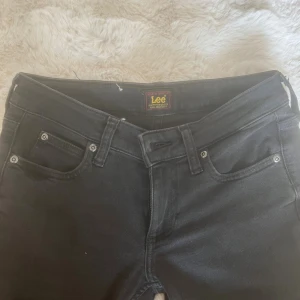 Svarta bootcut jeans från Lee - Snygga svarta jeans från Lee med klassisk femficksdesign och bootcut-ben. Jeansen har normal midja och Lee-logga på bakfickan samt bak i linningen. Tillverkade i mjukt denimtyg som sitter skönt hela dagen. Aldrig använda, nypris 1200kr. (Min kamera är sönder) därför är bilderna suddiga. Skriv för frågor 