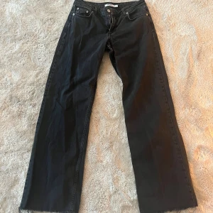 Svarta populära jeans från NA-KD - Svarta jeans från NA-KD i modell med raka, vida ben och råa kanter nertill. Klassisk femficksdesign, bälteshällor och dragkedja med knapp. Snyggt minimalistiska och passar perfekt till sneakers eller boots. Lågmidjade och avklippta att passa runt 160-165