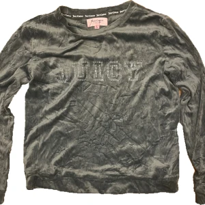 Grå tröja från Juicy Couture - grå långärmad tröja från Juicy Couture i sammet. Framsidan har glittriga stenar som bildar texten 'JUICY' och en rund halsringning. Är som en pyjamas tröja men går att använda till annat också.