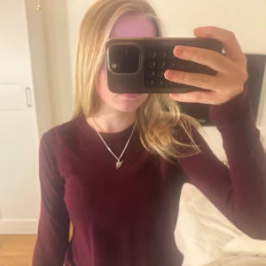 Vinröd långärmad tröja från Zara - Vinröd långärmad tröja från Zara med rund hals och guldknappar som detalj vid ärmsluten. Tröjan är i mjukt stickat material.