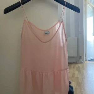 Ljusrosa tröja - Söt ljusrosa tröja  med tunna axelband och avslappnad passform.  har en enkel design med rynkad nederdel och är perfekt för varma dagar. Tillverkad i ett lätt och luftigt material.