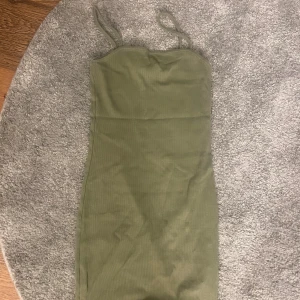 Olivgrön ribbad klänning  - Snygg olivgrön ribbad klänning från Amisu (New yourker) i storlek 36. Modellen är kort med smala axelband och figurnära passform. Materialet är mjukt och stretchig. Använt den en gång 