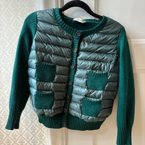 Grön Moncler cardigan - Jättesnygg moncler cardigan! Storlek M barnstorlek, vilket jag tror är som xxs. Den passar inte mig som kan ha Xs. Den har två små fläckar på en av fickorna, det som syns på bilden är det det är och i en av armhålorna är det ett litet hål som verkar ha lagats! Köpt på Plick men säljer vidare! 💗pris kan diskuteras