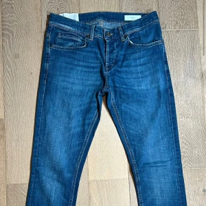 Blå dondup jeansbyxor - Snygga blå dondup jeansbyxor med klassisk femficksdesign och raka ben. Jeansen har en djupblå tvätt och kontrastsömmar, vilket ger en tidlös look. Perfekta för dig som gillar enkel och stilren denim.